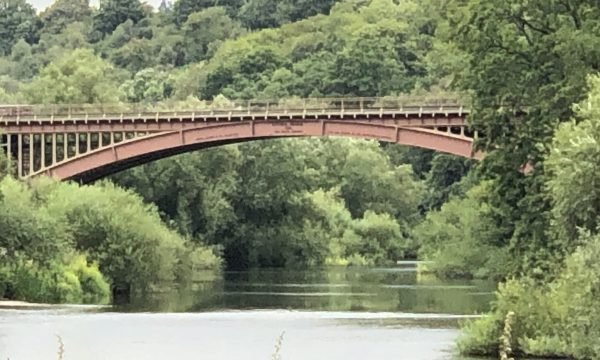 A red iron bridge spanning the river Severn.