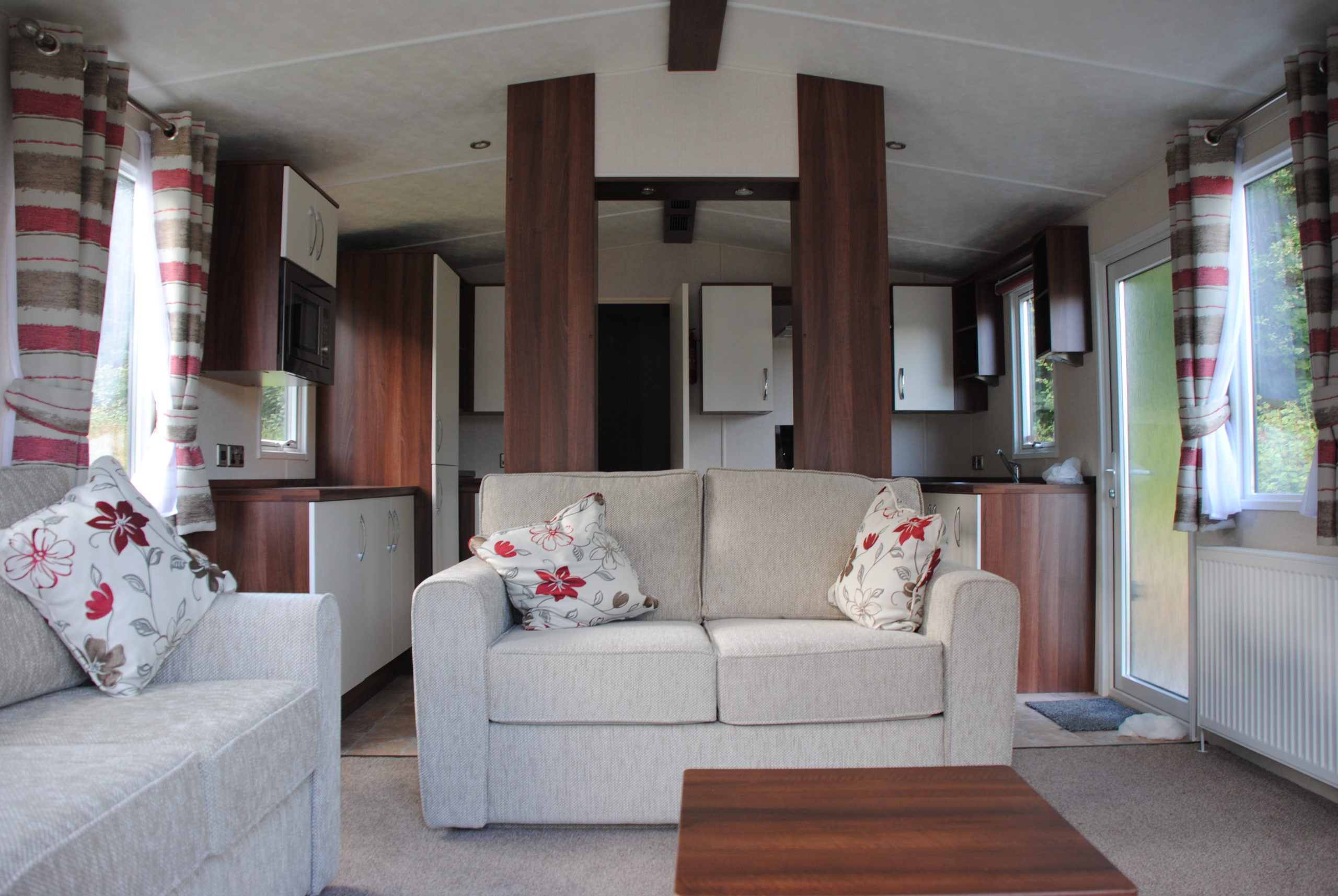 DSC_0660 the open plan, lounge of a static caravan holiday home with a fully fitted kitchen beyond