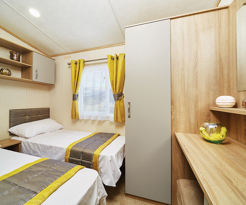 Twin beds in a white linen in a large twin bedroom of a static caravan at Lodge Coppice holiday Park