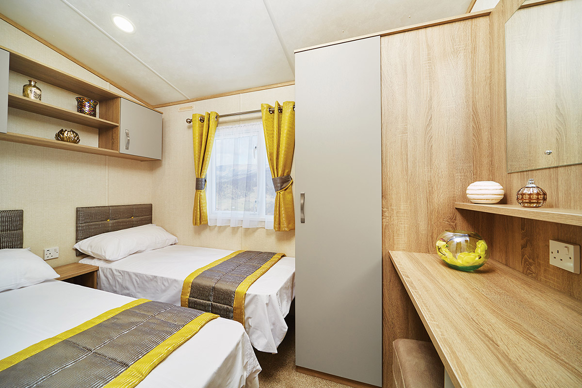 Twin beds in a white linen in a large twin bedroom of a static caravan at Lodge Coppice holiday Park