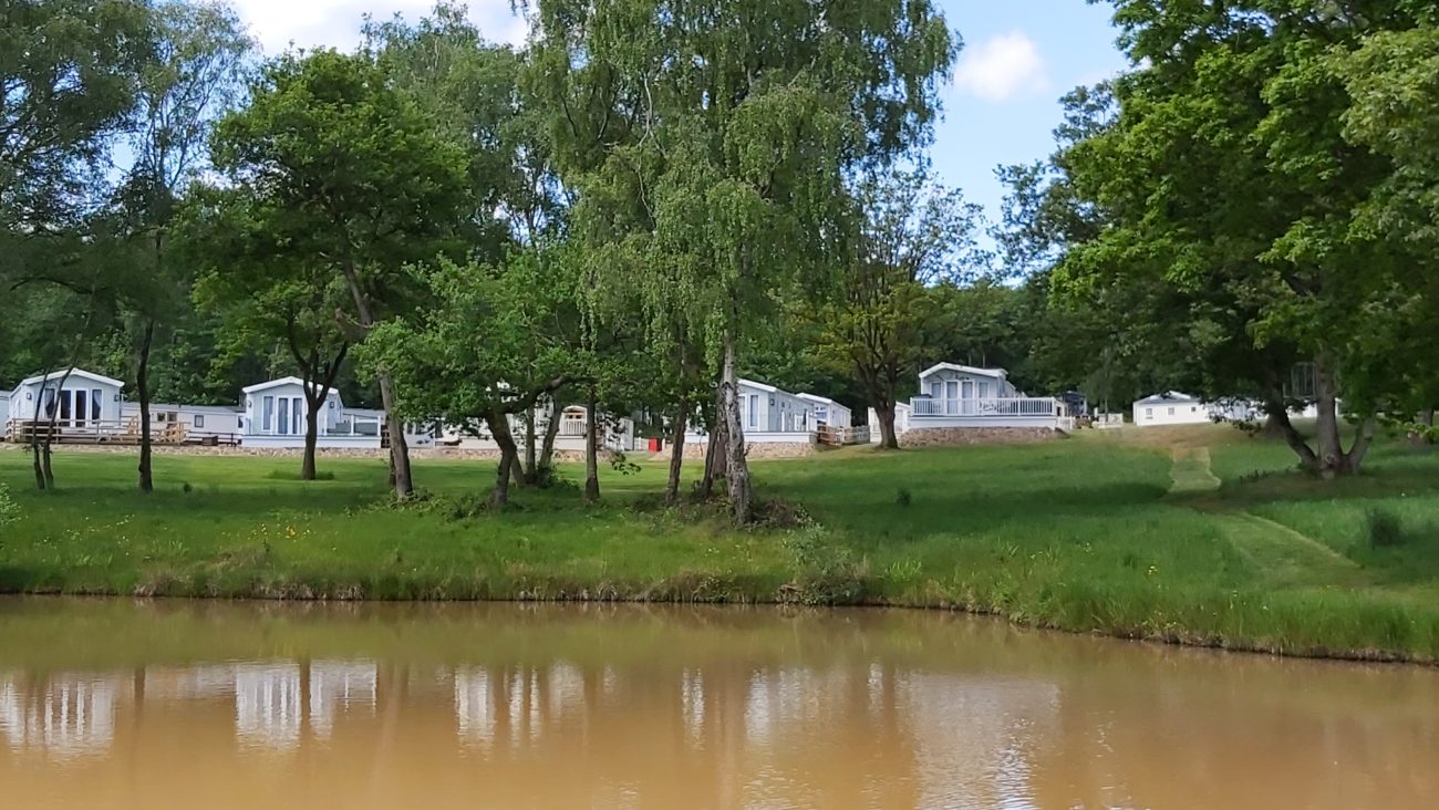 a cool fishing pool with 5 static caravans on the far side