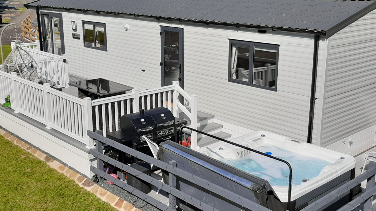 A creamy grey grey static caravan with contrasting charcoal grey roof and windows.