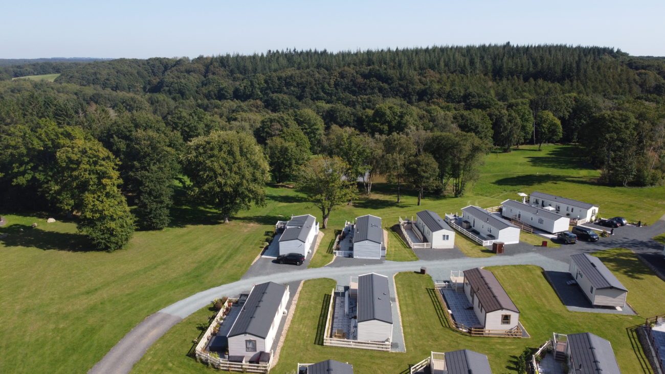 An angled aerial view of Lodge Coppice showing 11 well-spaced holiday homes and the Wyre Forest stretching into the distance.