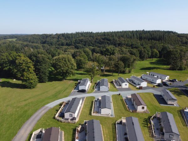 An angled aerial view of Lodge Coppice showing 11 well-spaced holiday homes and the Wyre Forest stretching into the distance.