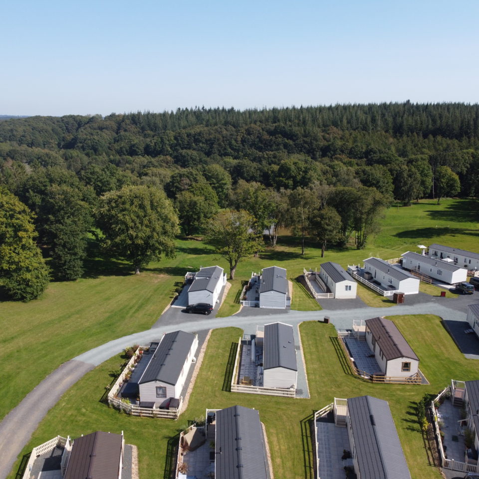 An angled aerial view of Lodge Coppice showing 11 well-spaced holiday homes and the Wyre Forest stretching into the distance.
