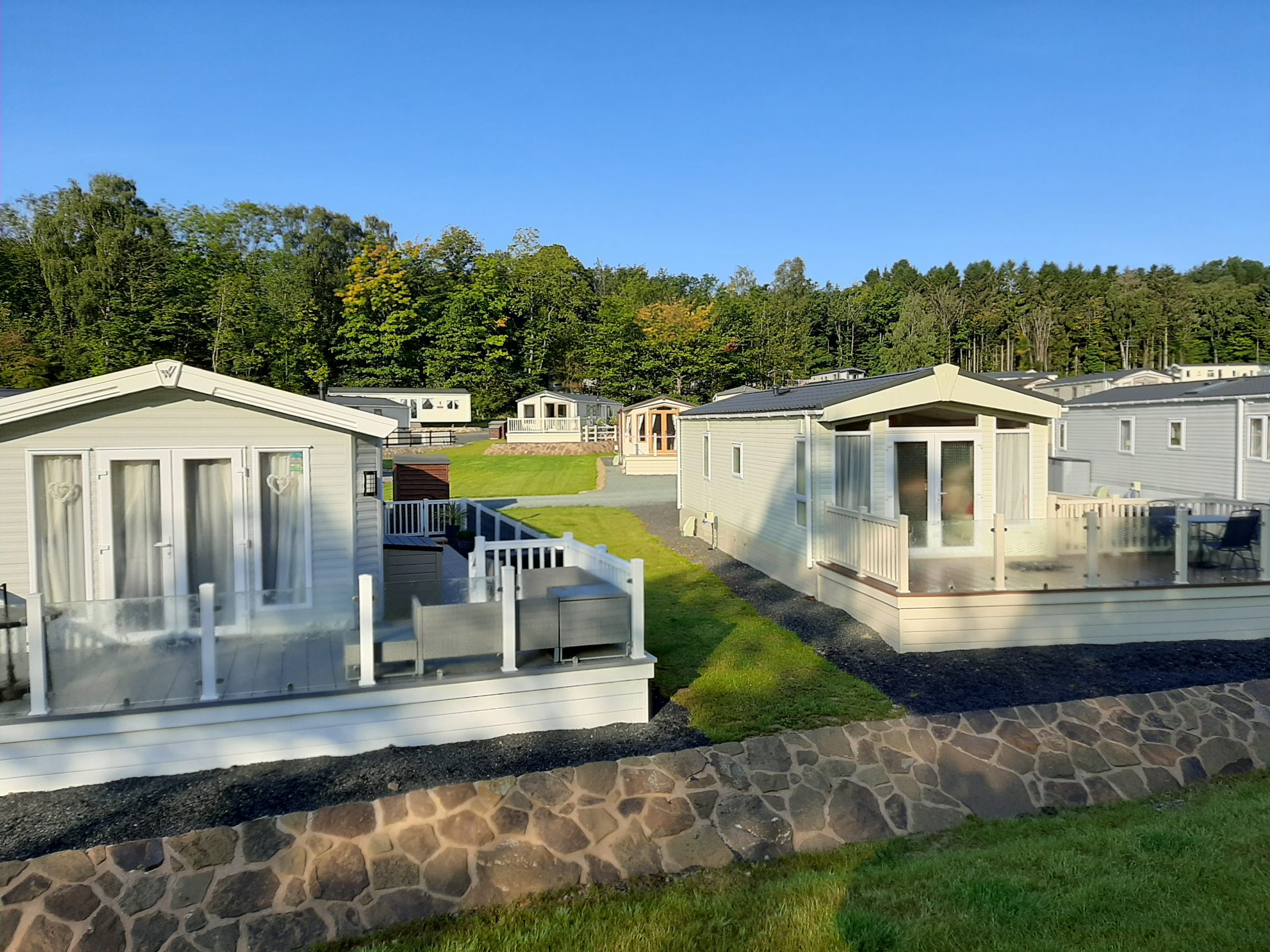 View across lodge coppice with well spaced static caravan holiday homes, complete with balustrades around the decking