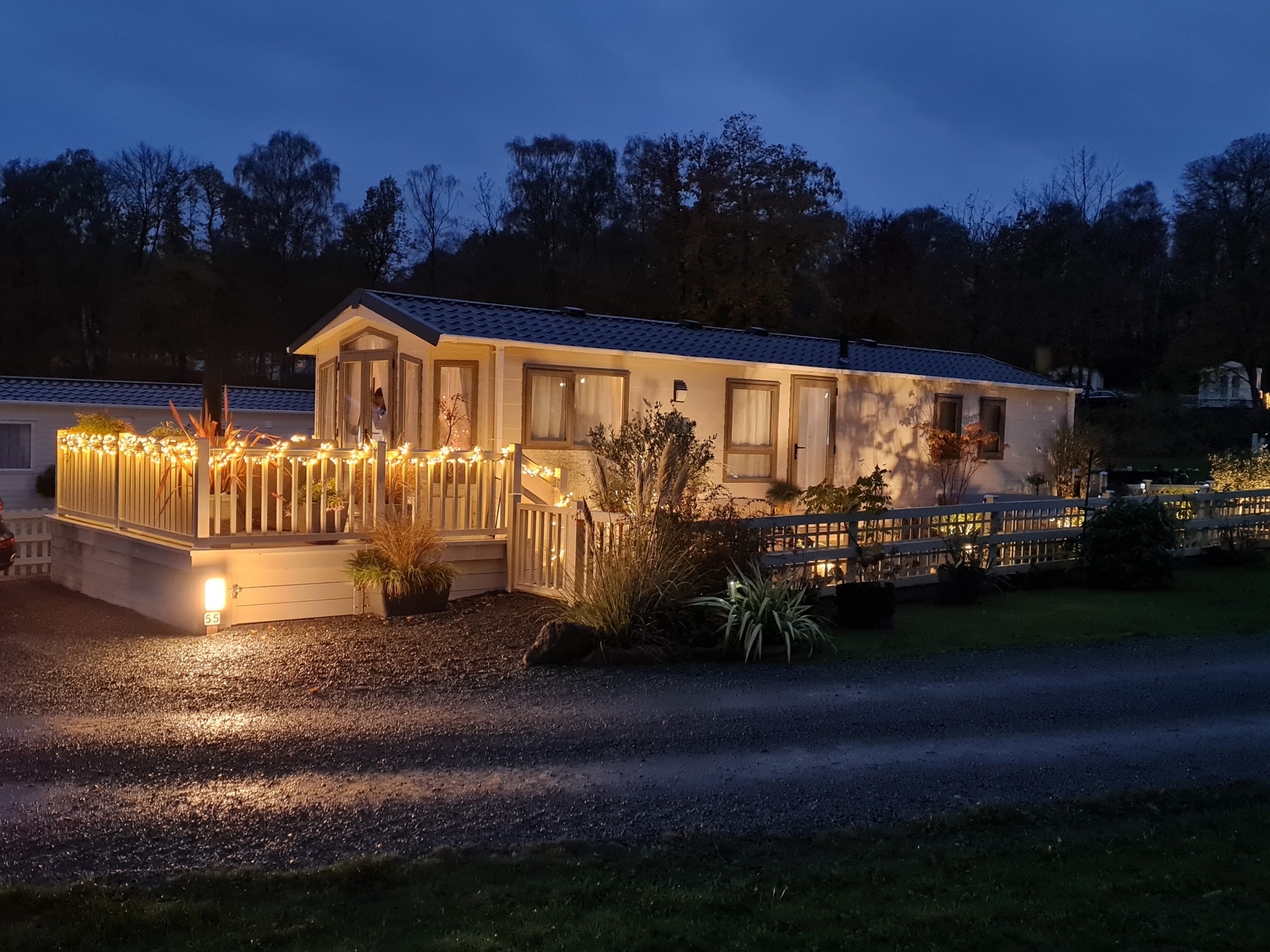 View of a lodge coppice static caravan illuminated with at night with external decking and balustrade lights