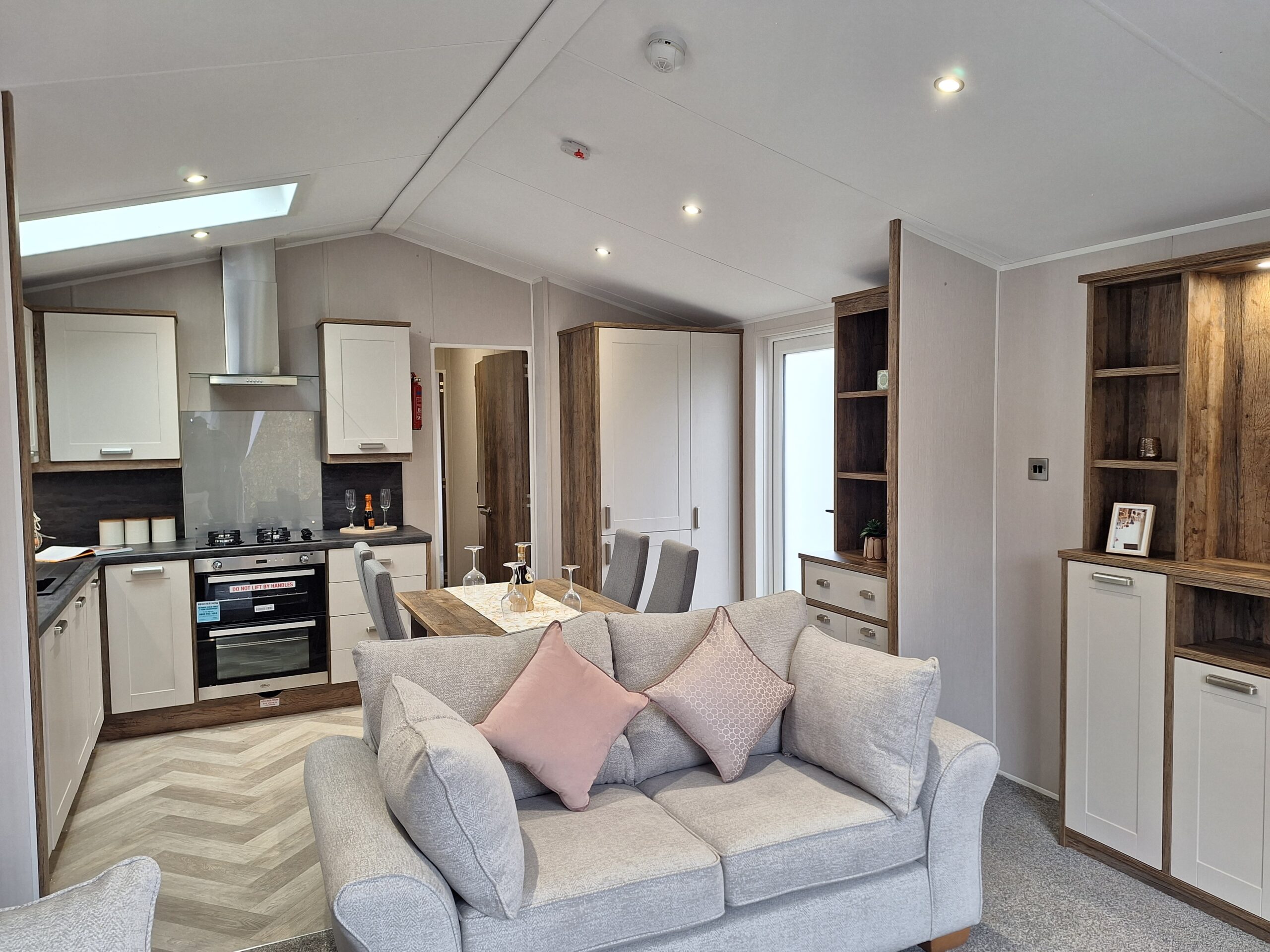 A twin sofa in the foreground of an open plan static caravan at Lodge Coppice with kithen behind